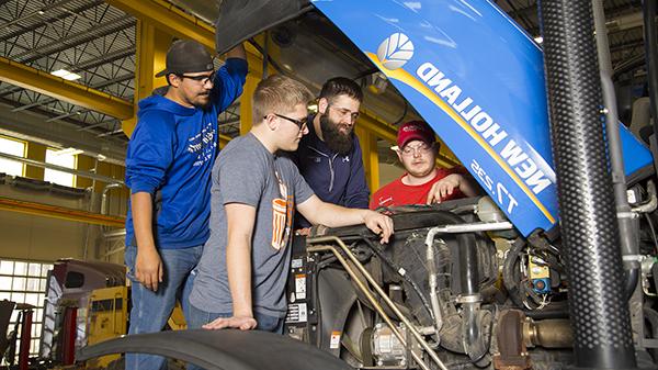 Students under hood of New Holland tractor